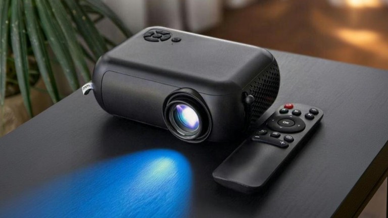 Smart mini projektor s diaľkovým ovládačom a modrým svetlom ako praktický darček na domáce premietanie na produktovej fotografii.
